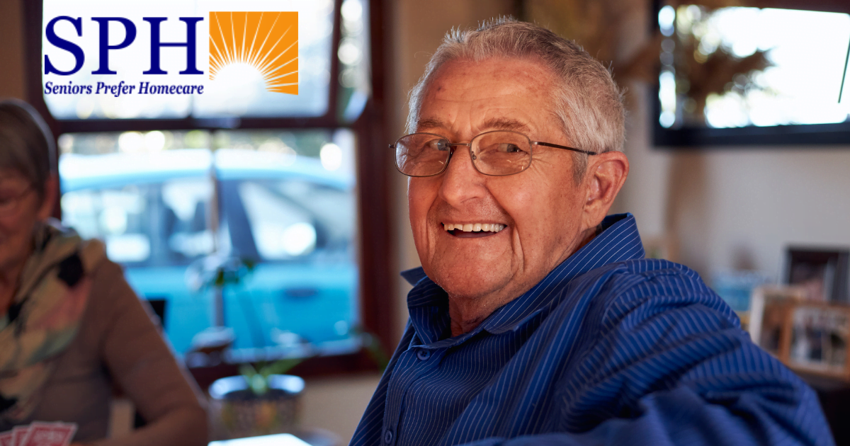 Smiling senior man is sitting at a table and is happy as a result of successful long-distance caregiving.