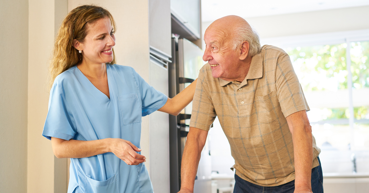 Caregiver smiling at senior man using a walker