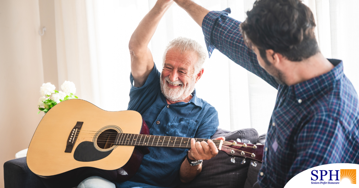 A smiling son high fives his happy elderly father as he plays the guitar, showing the positive effect music can have on people, including those with dementia.