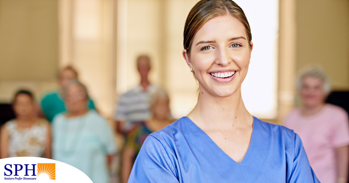 A professional caregiver smiles with seniors behind her, showing how a job with a caregiver agency can be a good choice.