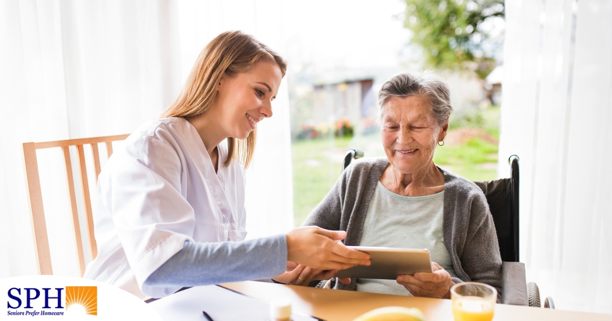 A professional caregiver smiles as she helps a happy senior client with her tablet, showing that she is managing caregiving stress well.