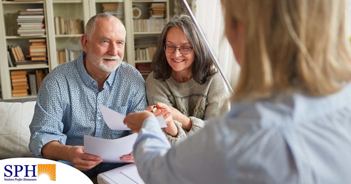 An older couple receives and considers papers from a woman, representing someone considering long-term care insurance.