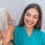 A caregiver smiles with an older client showing the results of successfully starting a new caregiving job.