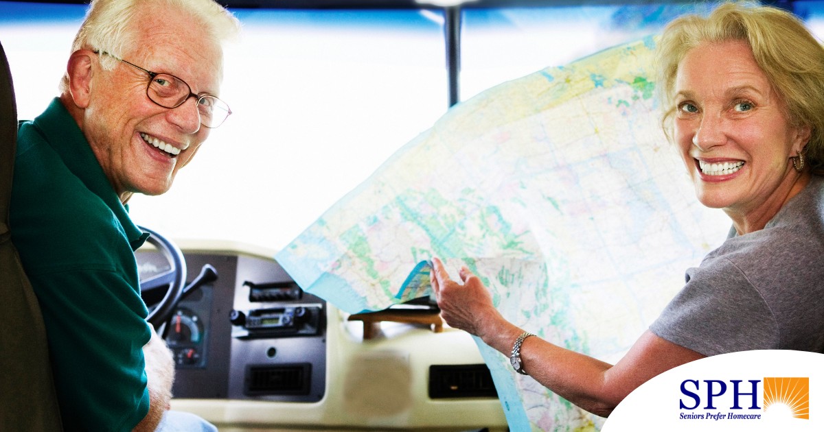 An older couple looks back smiling from the front of an RV, representing how day trips for seniors can help boost the mood of everyone.