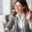 A well-dressed woman smiles and says hi on a videoconference, representing a candidate who is well-prepared for a caregiver interview.