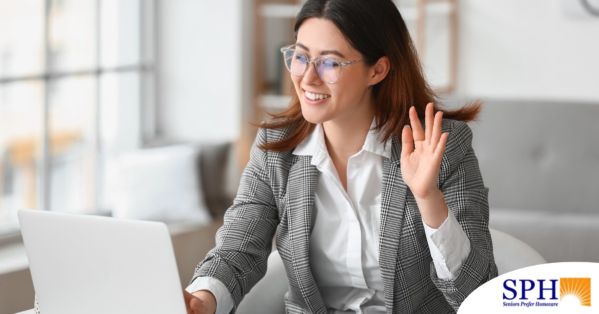 A well-dressed woman smiles and says hi on a videoconference, representing a candidate who is well-prepared for a caregiver interview.