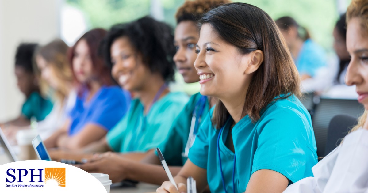 Several students in scrubs happily attend a class, representing caregiver training.