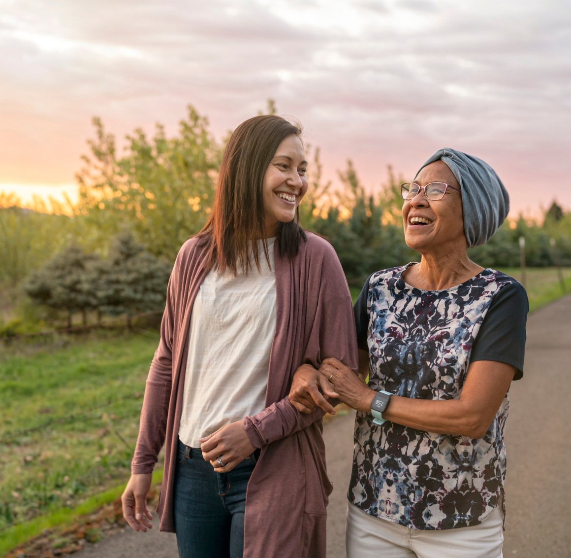 Personal Care in Cottondale, AL Two women walking arm-in-arm outdoors at sunset, representing compassionate personal care in Cottondale, AL.