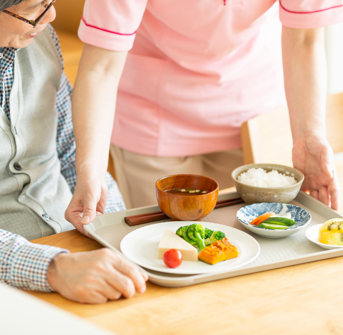 meal planning services in Cottondale, caregiver serving a meal tray to a senior | meal planning services in Cottondale, AL